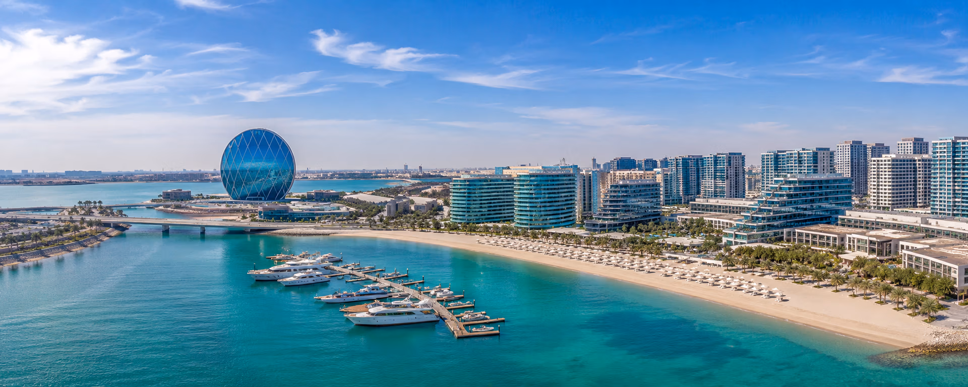 Panoramic aerial view of Al Raha Beach in Abu Dhabi featuring luxury waterfront residences, marina, Aldar Headquarters, private beaches, and premium residential communities.